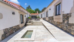A courtyard with a stone pathway, a small water feature, and outdoor seating. - Casa da Ponte de Penas (Melide)