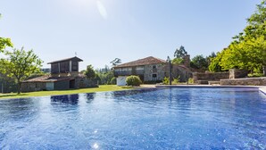 A swimming pool with a stone house in the background. - Casa da Ponte de Penas (Melide)