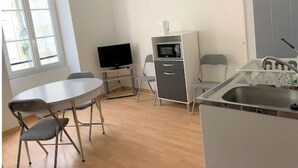 A compact kitchen with a dining area, a microwave, a TV, and a sink. - Studio Centre Ville et Bord de mer (Les Sables-d'Olonne)