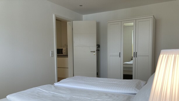 A bedroom with a bed, a wardrobe, and a mirror. - Apartment house "Charibi" a well-kept residential complex near the beach (Dahme)