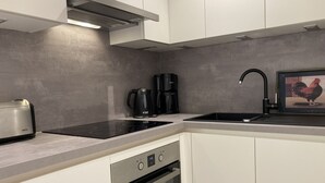 A modern kitchen with a built-in oven, a stovetop, a coffee maker, and a kettle. - Apartment house "Charibi" a well-kept residential complex near the beach (Dahme)
