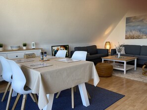 Un salon moderne avec un coin repas, comprenant un canapé, une table basse et une table à manger avec des chaises.