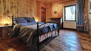 Une chambre aux murs lambrissés, avec un lit, une fenêtre avec des rideaux et un radiateur.