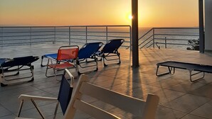 A terrace with lounge chairs and a view of the sunset over the sea. - Charming 4-bed Villa in Pefkali (Corinth)