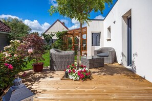 A wooden deck with wicker furniture and potted plants.