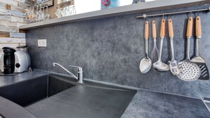 Una cuina amb un disseny modern, que destaca per un doble rentaplat, una cafetera i diversos utensilis penjats a la paret.