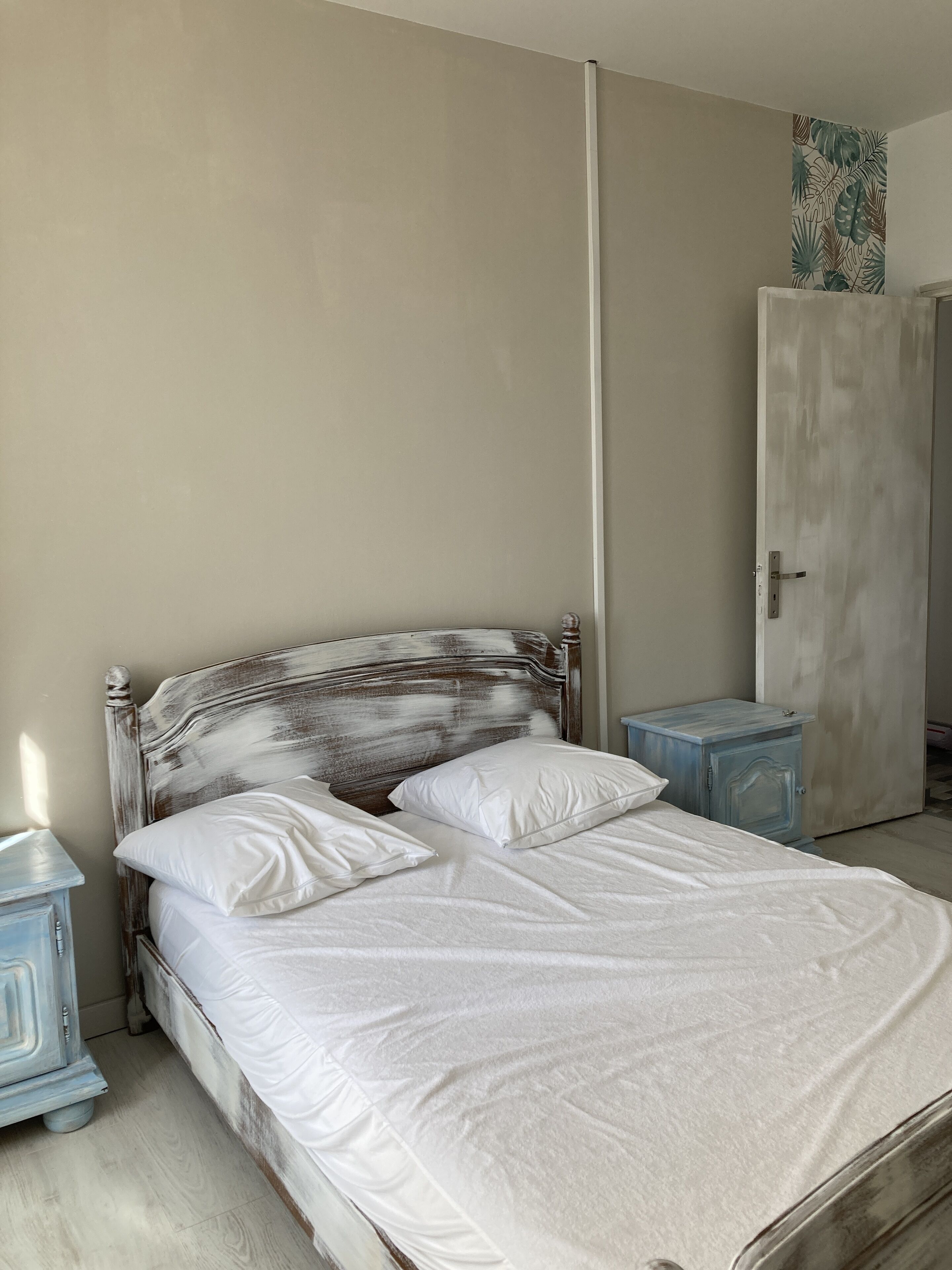 Un dormitorio con cama, mesita de noche, armario y puerta.