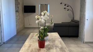 A modern living room with a wooden coffee table, a red flower pot, and white orchids. - Country house with swimming pool (Coulx)