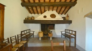 A rustic room with a wooden ceiling, a fireplace with a stone surround, and several wooden benches.