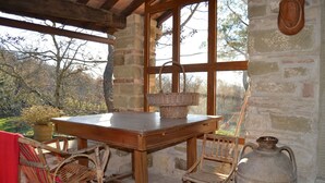 A rustic wooden table with wicker chairs, a large vase, and a basket on the table.