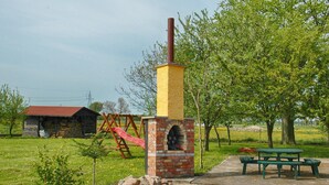 Ein Backofen aus Ziegelsteinen mit Schornstein, ein Picknicktisch und ein Spielplatz mit Rutsche.