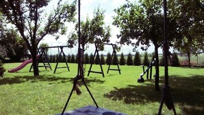 Ein Picknicktisch mit Tasse, Schaukel und Rutsche in einer grünen Parkanlage.