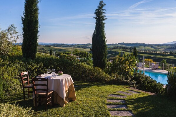 A table set outdoors with a view of a swimming pool and rolling hills in the background.