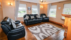 Ein Wohnzimmer mit einer schwarzen Ledersofa-Garnitur, einem schwarzen Leder-Relaxsessel und einer Holzkommode.
