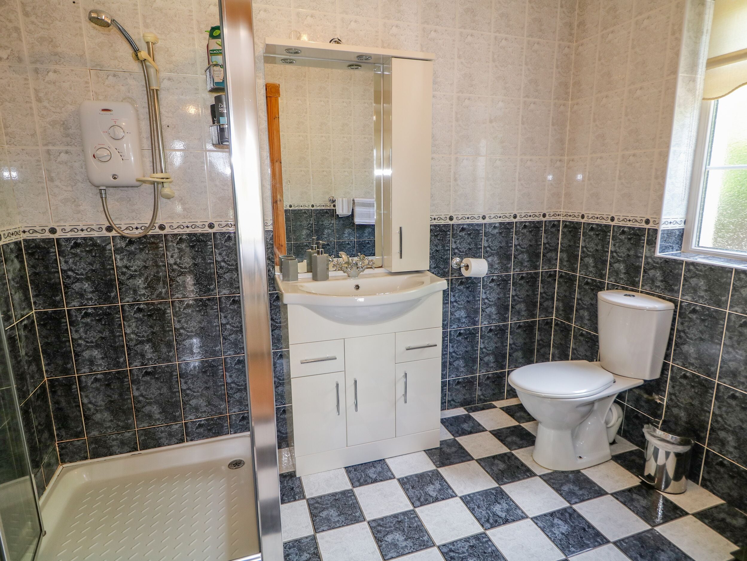 Ein Badezimmer mit Dusche, Toilette, Waschbecken und Spiegel.