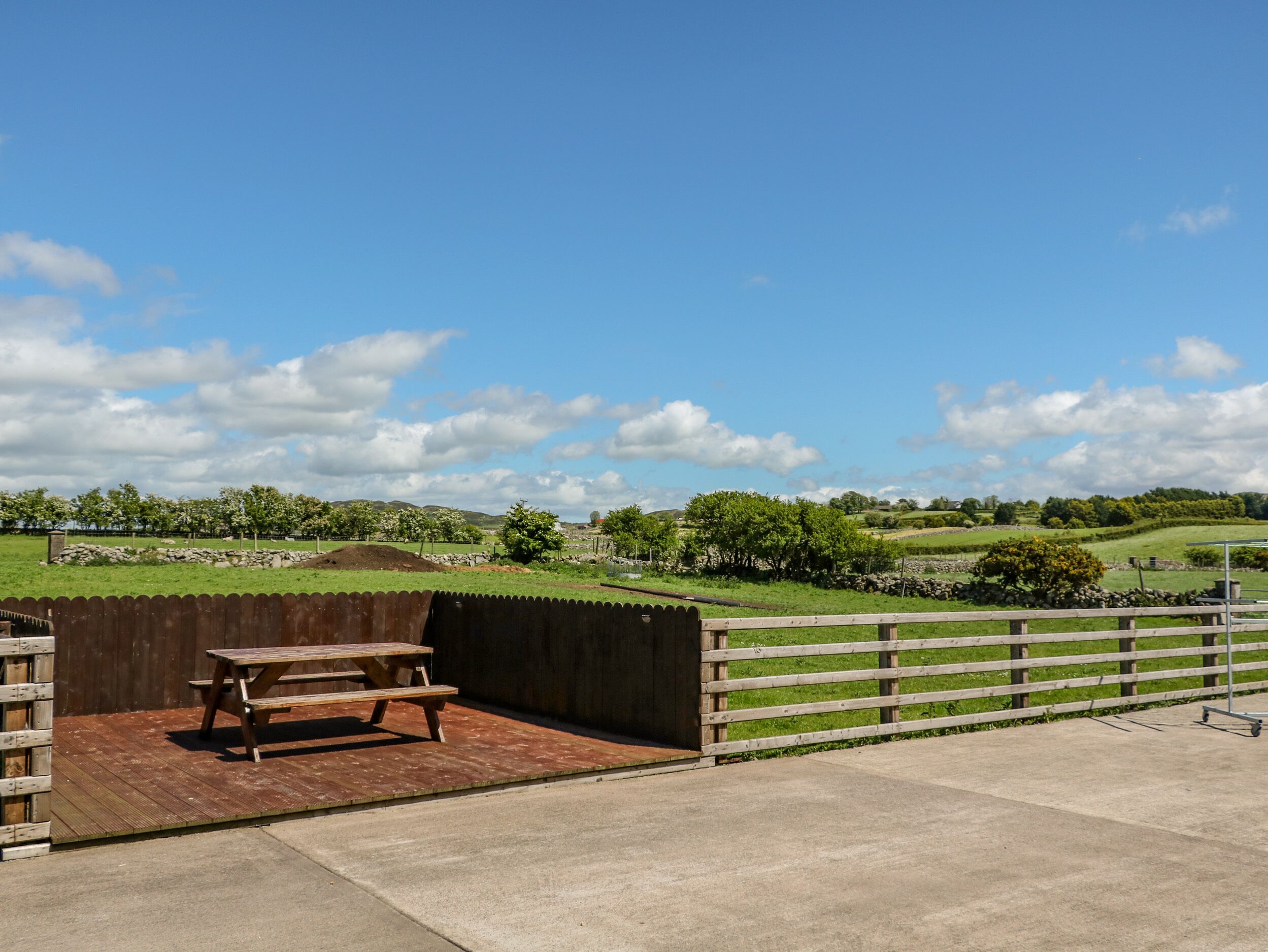 A patio with a picnic table and a view of rolling hills and a clear sky.