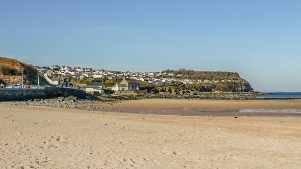 Ein Küstenort mit Häusern auf einer Klippe mit Blick auf den Strand.