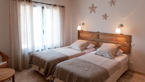A double room with two beds, a wooden headboard, and a window with curtains.