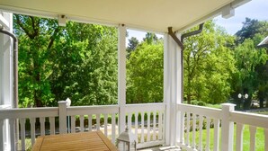 A wooden deck with a table and chairs, surrounded by white railings, overlooking a lush green landscape. - Comfort plus apartment with 1 bedroom and balcony on the upper floor (Ostseebad Binz)