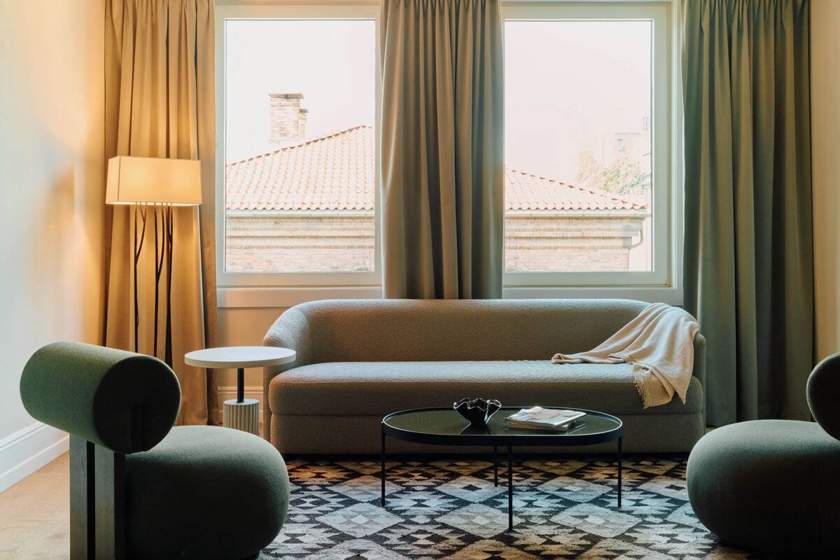 A modern living room with a sofa, two armchairs, a small round table, and a patterned rug.