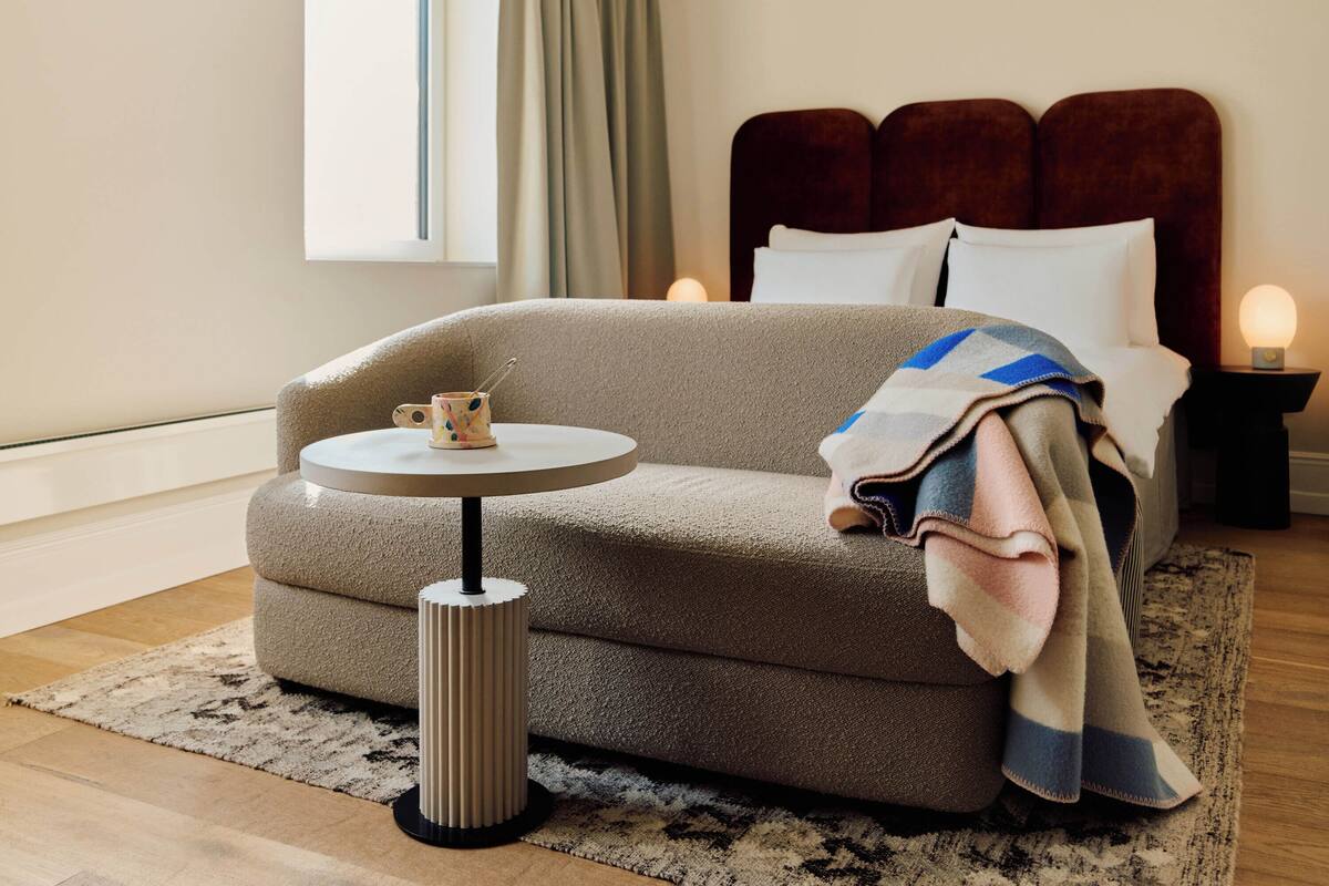 A modern bedroom with a sofa, a small round table, and a bedside lamp.