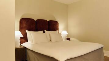 A neatly made bed with a brown headboard, white bedding, and two bedside lamps.