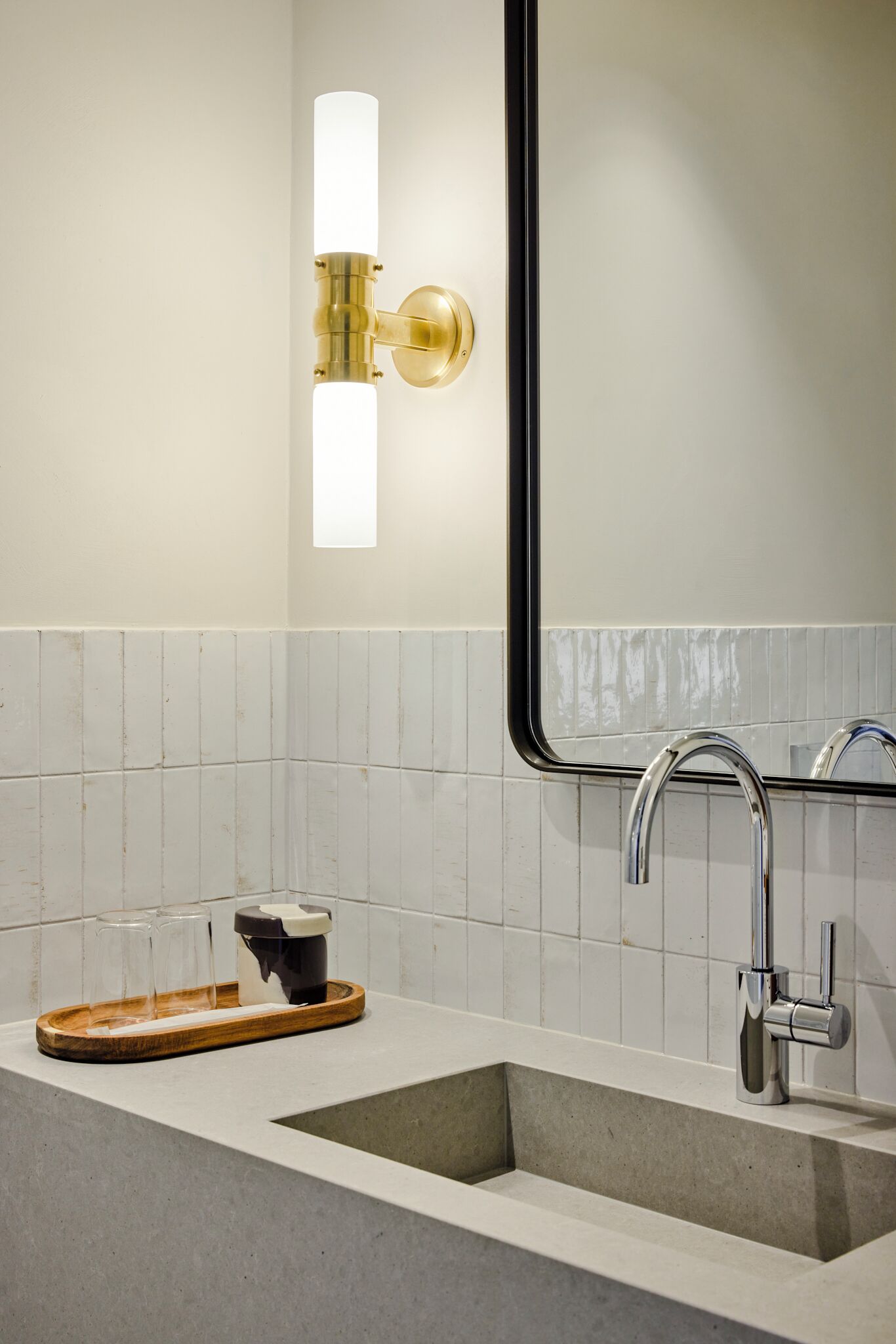 Un baño moderno con un lavamanos rectangular, grifo cromado e iluminación empotrada.