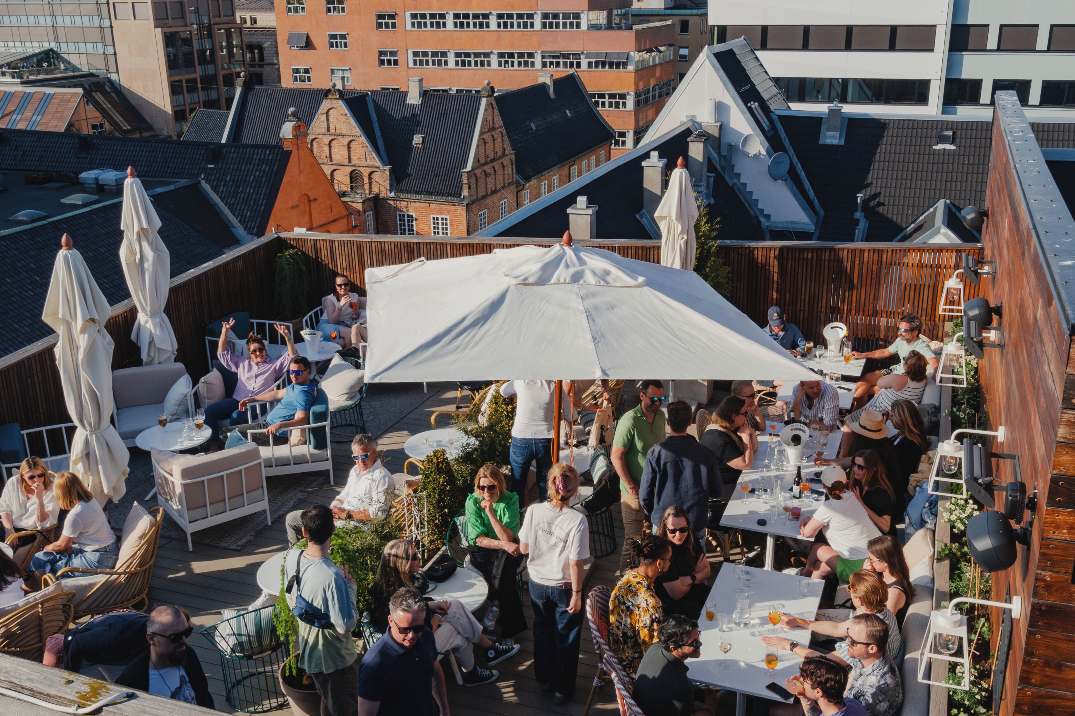 Un espace extérieur aménagé avec des tables et des parasols, entouré de bâtiments.