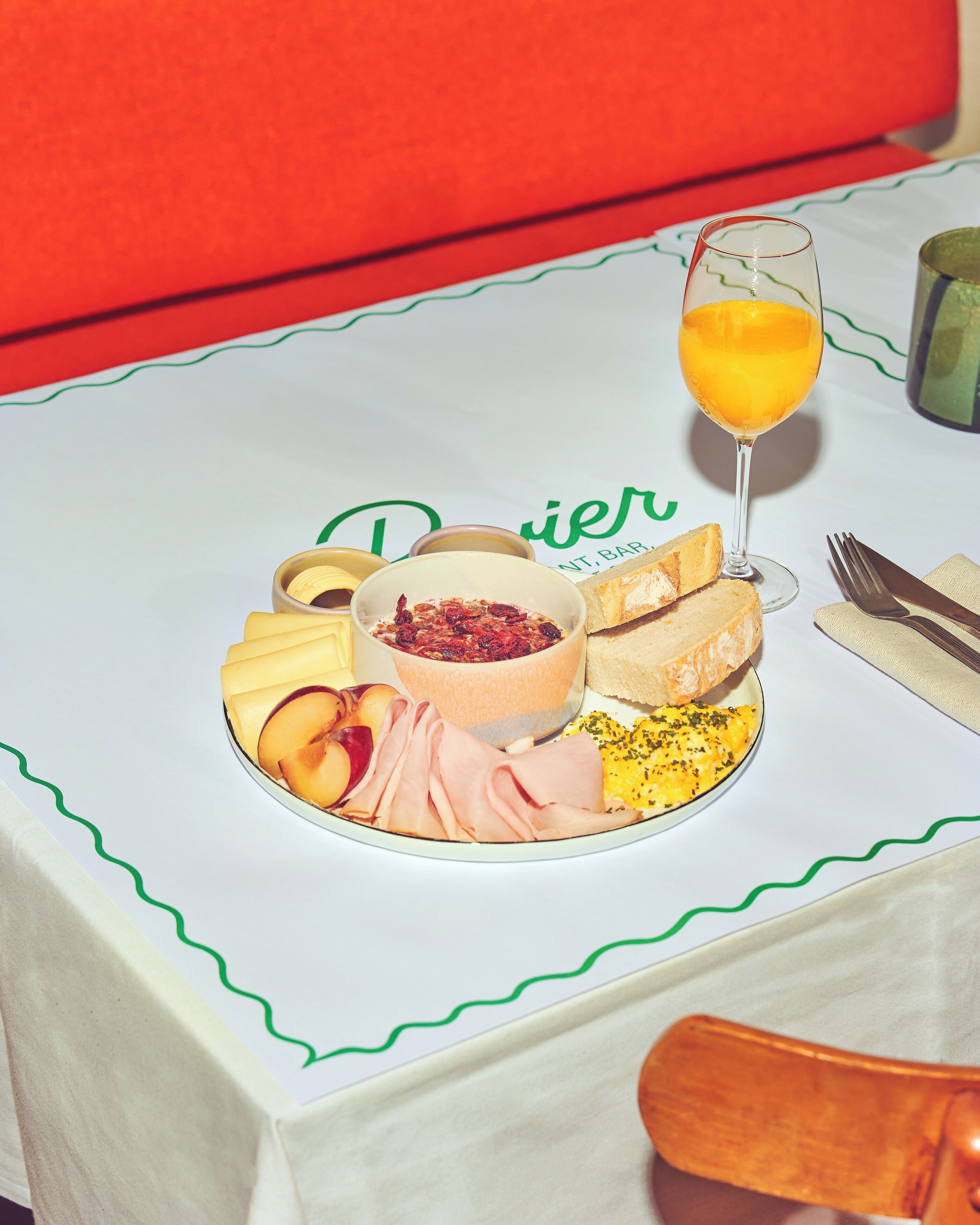 A breakfast setting with a plate of food, a glass of orange juice, and a bowl of fruit salad.