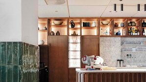 A modern kitchen with a wooden island, marble countertops, and a round dining table with a candle. - Revier (Oslo)