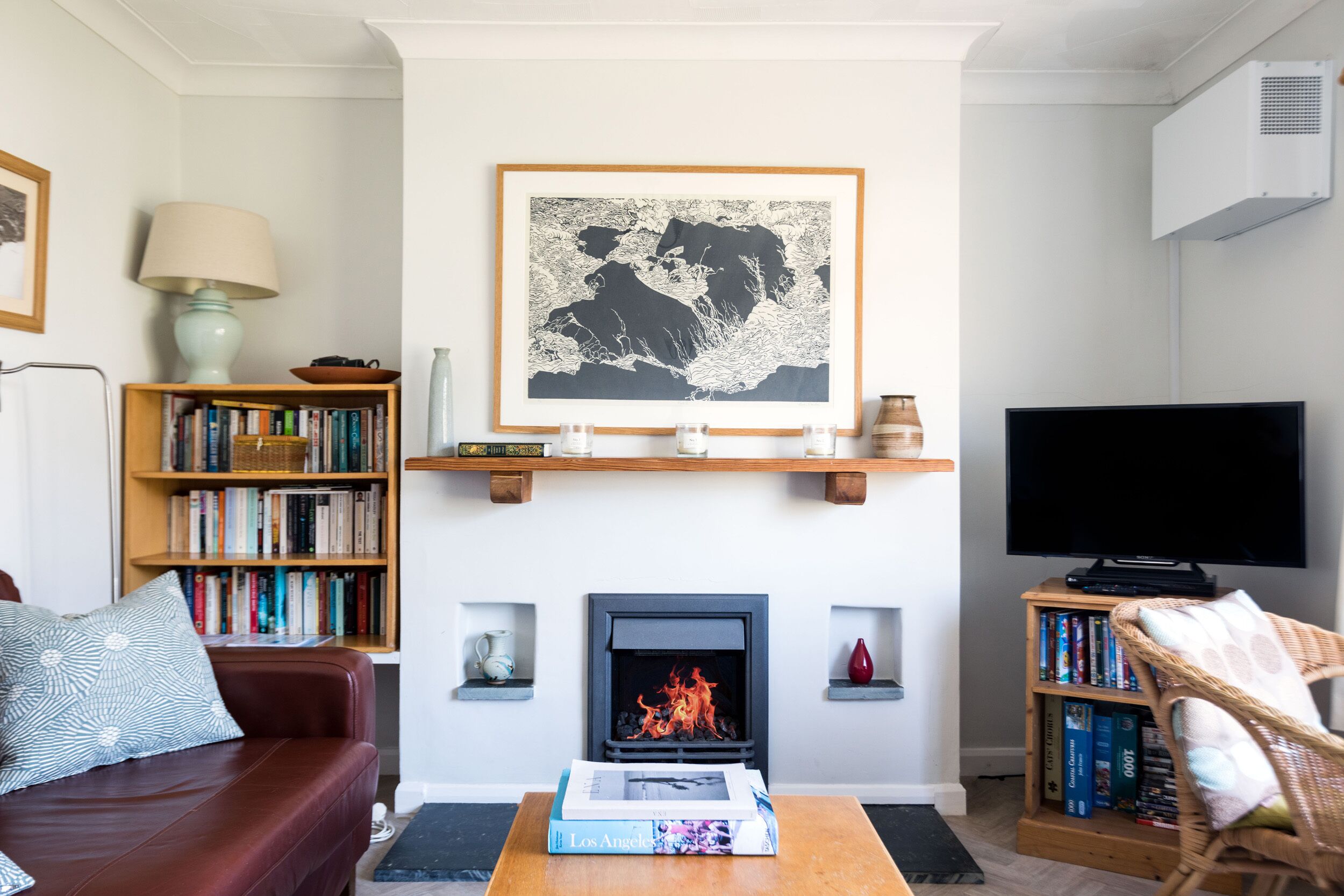 Ein Wohnzimmer mit Kamin, Bücherregalen, einem Fernseher und einer Couch.