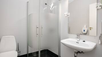 Een moderne badkamer met een douchecabine van glas, een wit wastafelmeubel en een toilet.