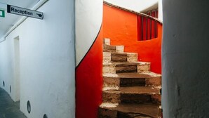 Un espace d’accueil avec un panneau indicateur, un escalier aux murs rouges et un mur blanc avec une porte.