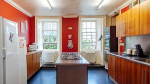 Une cuisine avec des meubles en bois, un îlot central et une fenêtre donnant sur un espace verdoyant.
