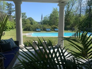 Un espacio al aire libre techado con piscina, sillas de descanso y una bandera.
