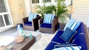 A covered porch with wicker furniture, including a sofa and chairs, adorned with blue and white striped cushions. - Spacious Adirondacks Retreat • 6BR, Heated Pool. Lake Champlain  (Willsboro)