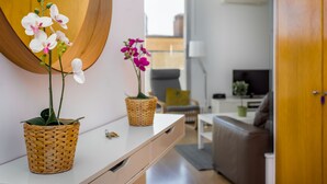 Un salon moderne avec un canapé blanc, une table basse et deux orchidées en pot disposées sur une console blanche.