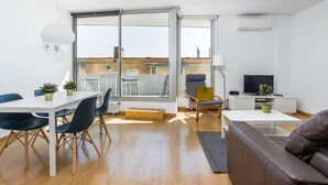 Un salon moderne comprenant un coin repas, de grandes portes-fenêtres coulissantes, un téléviseur et un canapé.