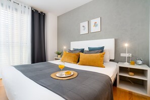 A modern bedroom with a large bed, bedside tables, a bedside lamp, and a clock.