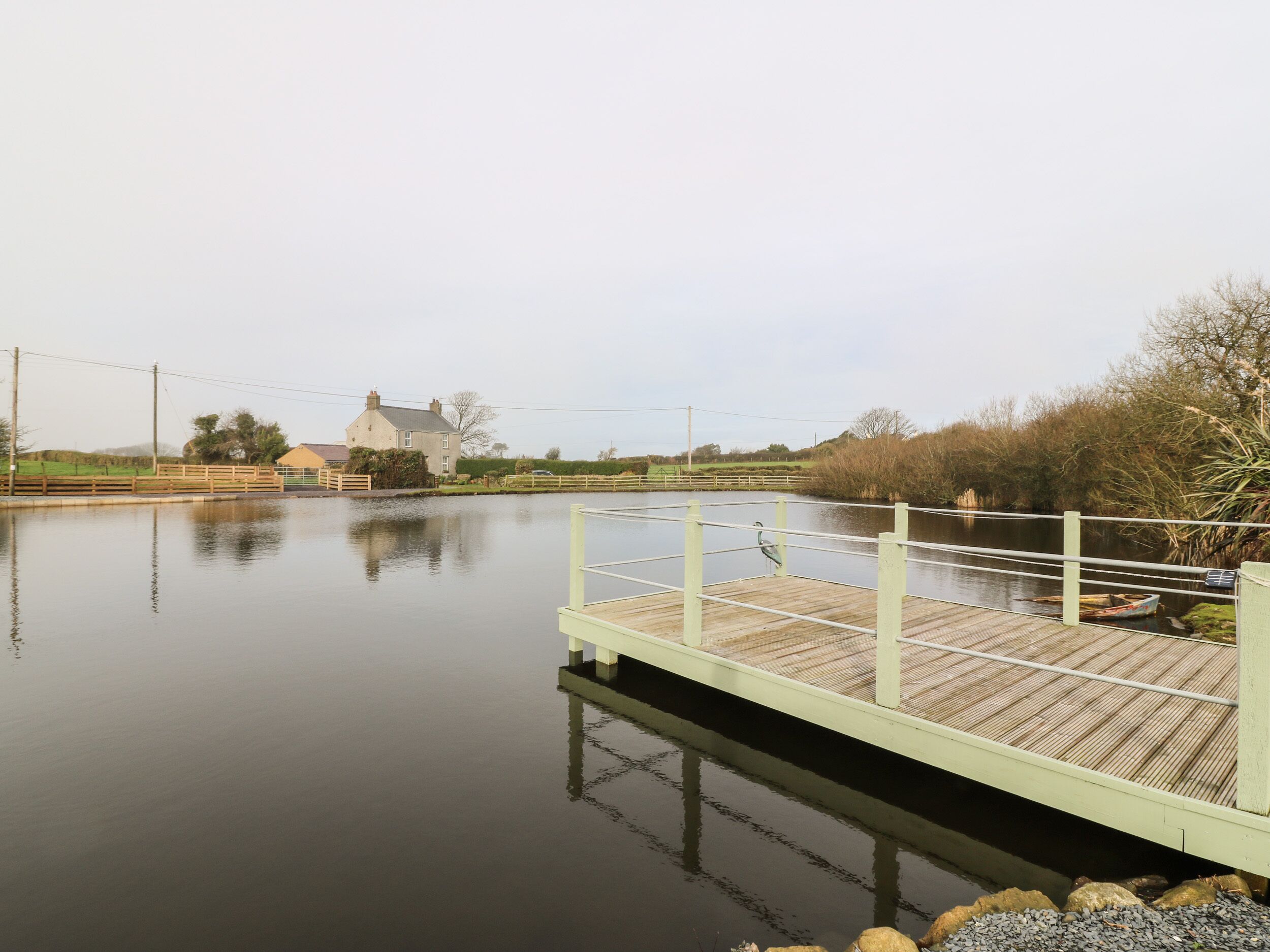 Un río tranquilo con un muelle de madera y una casa al fondo.