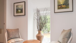 A room with two armchairs, a wooden table, and two framed paintings on the walls. - Old Manse (Muir of Ord)