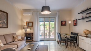 Een moderne woonkamer met een bank, salontafel, eettafel, stoelen en een wereldbol op een kast.