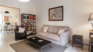 Een woonkamer met een bank, fauteuil, salontafel, boekenkast en een kaart aan de muur.