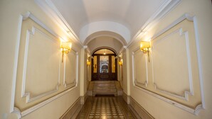 A hallway with a patterned floor, white walls, and two wall-mounted lamps. - Dolcevita Terrace (Roma)