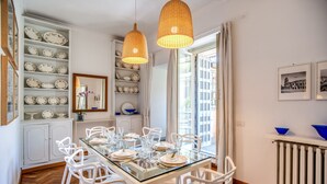 A dining area with a glass table, white chairs, and a shelf with plates. - Dolcevita Terrace (Roma)