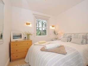 A bedroom with a bed, a dresser, a window, and wall-mounted lights.