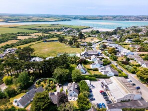 Vista aérea de un pueblo costero con casas residenciales, un extenso campo abierto y una playa.