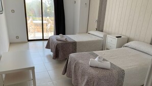 A hotel room with two beds, a small table, and a view of the outdoors. - Hotel Aloha (Burriana)