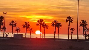 A sunset over a beach with palm trees and a clear sky. - Hotel Aloha (Burriana)