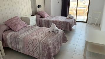 Habitació d'hotel amb dos llits, una taula de treball i vista a un pàrquing.